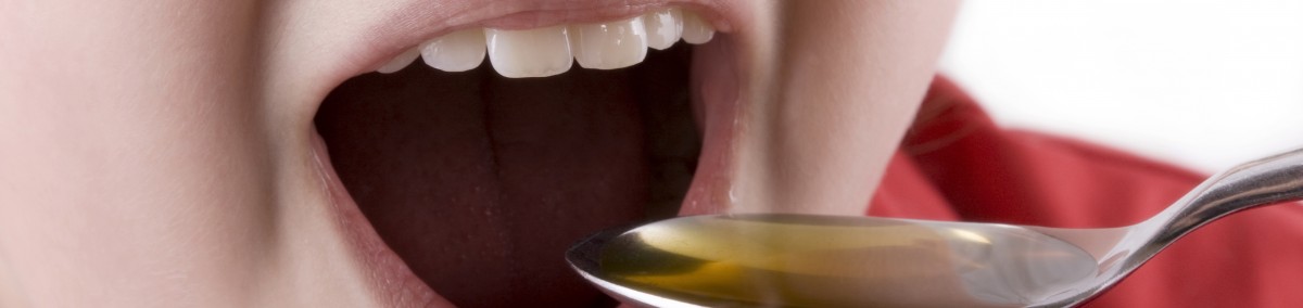 Young girl about to take medication or cod liver oil from a spoon